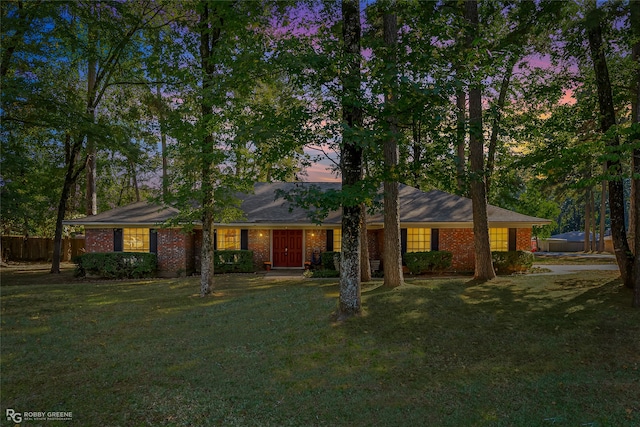 ranch-style house with a yard, fence, and brick siding