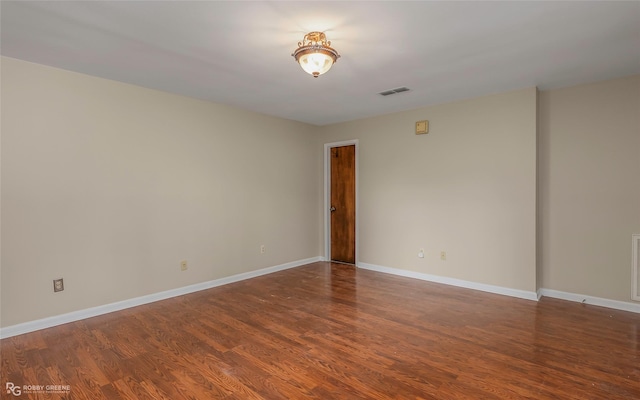 unfurnished room featuring visible vents, baseboards, and wood finished floors