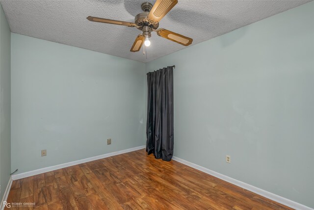 unfurnished room featuring a ceiling fan, wood finished floors, baseboards, and a textured ceiling