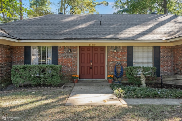 property entrance featuring brick siding and roof with shingles