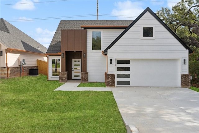 view of front of home with central air condition unit, a front yard, and a garage