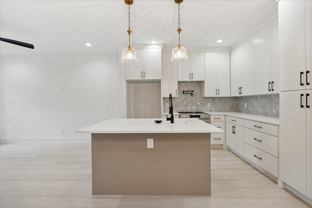 kitchen featuring backsplash, white cabinetry, pendant lighting, and an island with sink