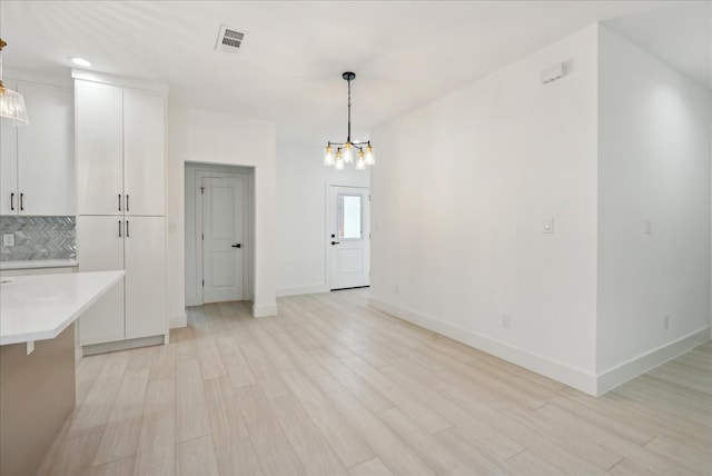 kitchen featuring light hardwood / wood-style floors, a notable chandelier, tasteful backsplash, and hanging light fixtures