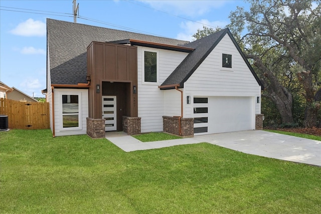 view of front of home with a front yard, central AC unit, and a garage