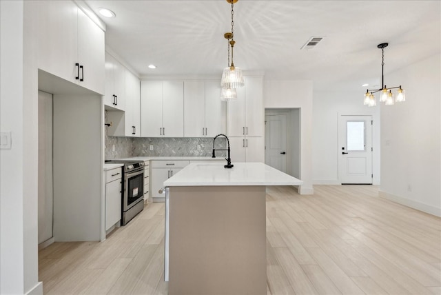 kitchen with sink, white cabinetry, decorative light fixtures, and stainless steel range with electric cooktop