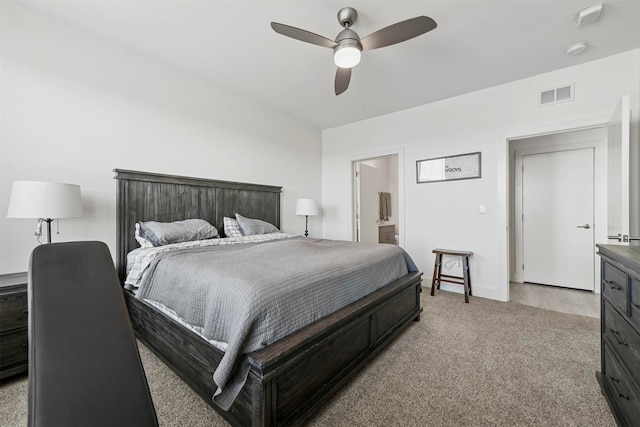 carpeted bedroom with ensuite bathroom and ceiling fan