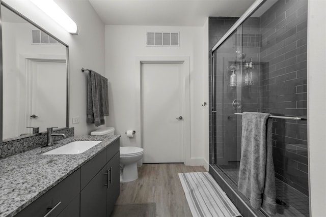 bathroom featuring toilet, an enclosed shower, vanity, and wood-type flooring