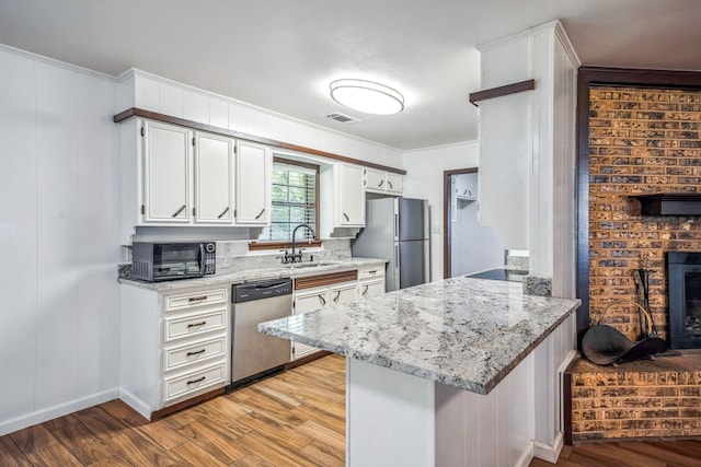 kitchen featuring kitchen peninsula, white cabinets, stainless steel appliances, and light wood-type flooring