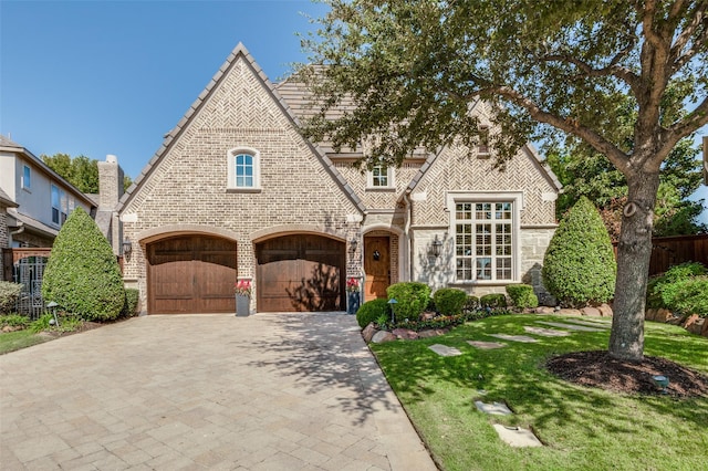 tudor home with a garage and a front yard