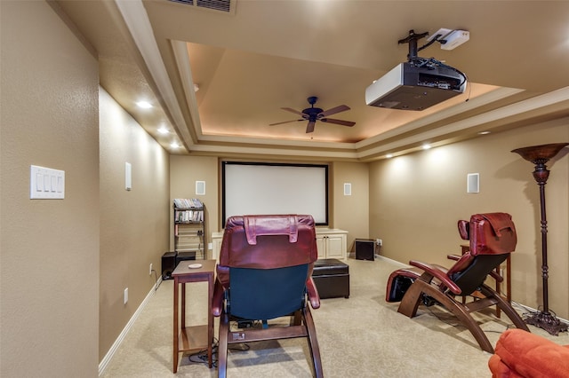 carpeted cinema room with a raised ceiling and ceiling fan