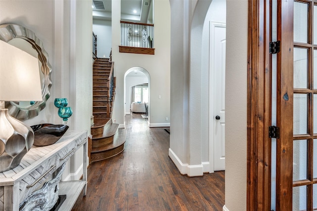 corridor featuring a towering ceiling and dark hardwood / wood-style floors