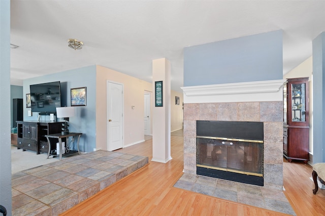 living room with hardwood / wood-style flooring and a tile fireplace