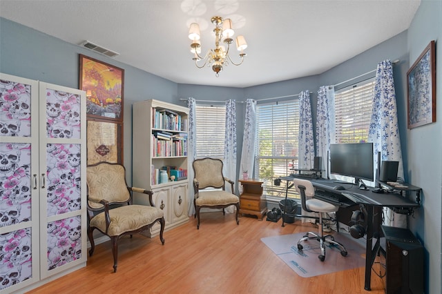 office with light hardwood / wood-style flooring and an inviting chandelier