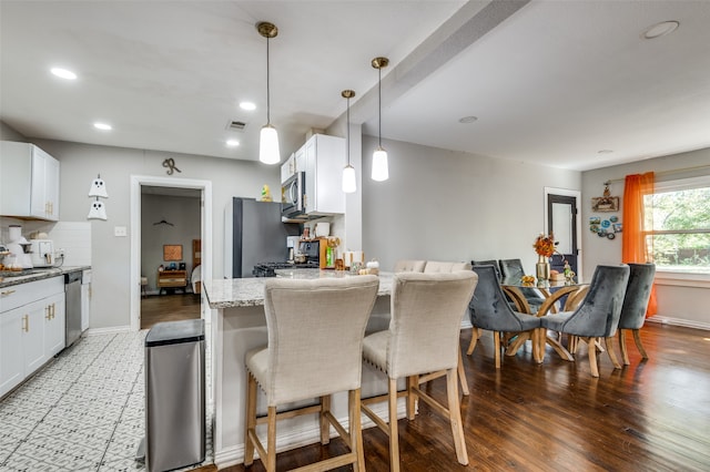 kitchen featuring light stone countertops, appliances with stainless steel finishes, a breakfast bar area, and white cabinets