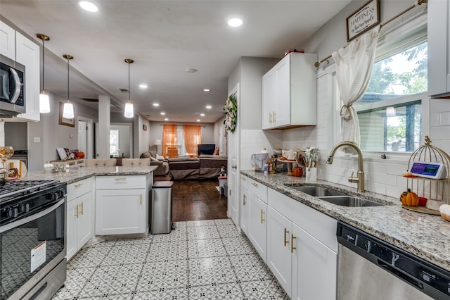 kitchen featuring white cabinetry, appliances with stainless steel finishes, decorative light fixtures, and sink