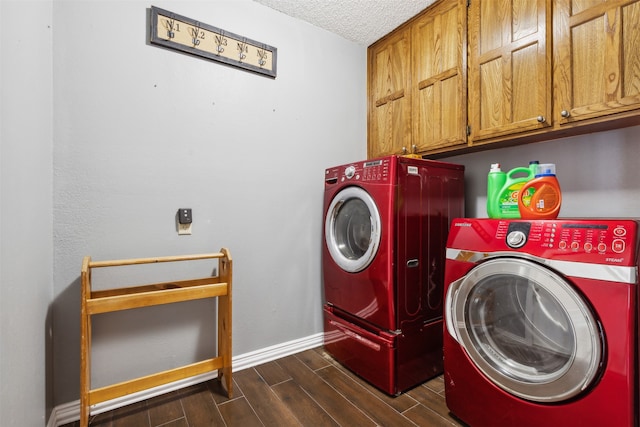 laundry room with dark wood-type flooring, a textured ceiling, washing machine and dryer, and cabinets