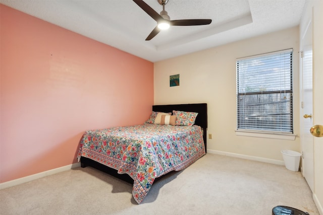 bedroom featuring ceiling fan, a textured ceiling, carpet, and a tray ceiling