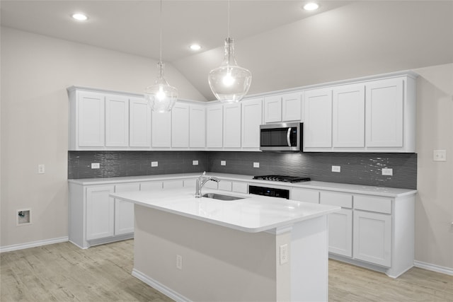 kitchen with white cabinetry, vaulted ceiling, sink, and decorative light fixtures