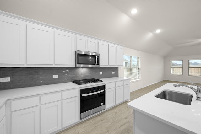 kitchen with white cabinetry, appliances with stainless steel finishes, sink, and lofted ceiling