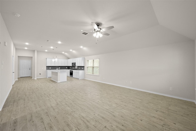 unfurnished living room with ceiling fan with notable chandelier, vaulted ceiling, and light wood-type flooring