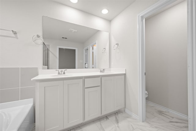 bathroom with toilet, vanity, and a tub to relax in