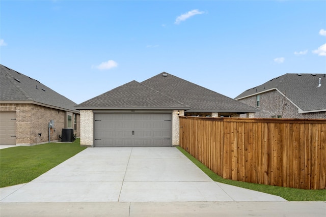 view of front of property with central AC, a garage, and a front lawn