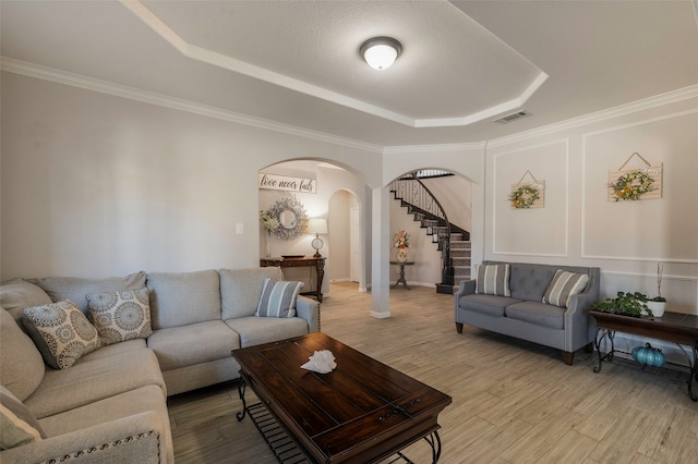 living room with light hardwood / wood-style floors, crown molding, and a raised ceiling