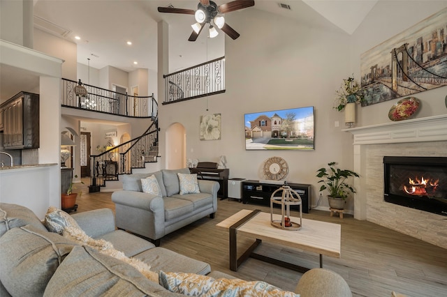 living room featuring ceiling fan, high vaulted ceiling, and light hardwood / wood-style flooring