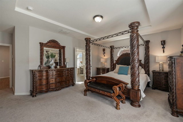 carpeted bedroom with ensuite bathroom and a tray ceiling