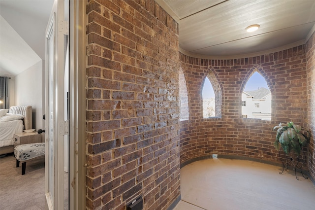 hallway with brick wall and light colored carpet