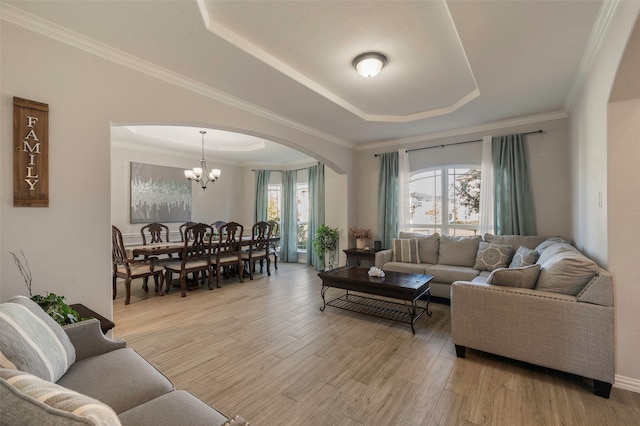 living room with light hardwood / wood-style floors, ornamental molding, plenty of natural light, and a raised ceiling