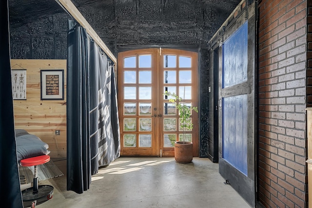 doorway to outside featuring french doors, concrete floors, and wooden walls