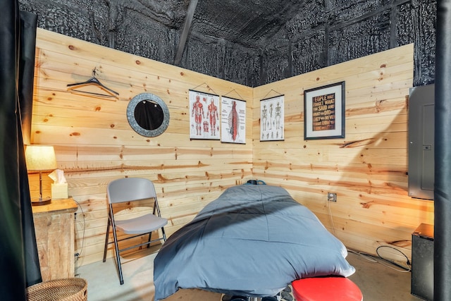 bedroom with concrete floors, wood walls, and electric panel