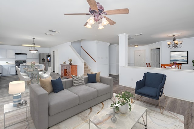 living room with ceiling fan with notable chandelier and light wood-type flooring