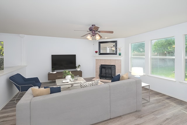 living room with hardwood / wood-style floors, ceiling fan, and a tiled fireplace