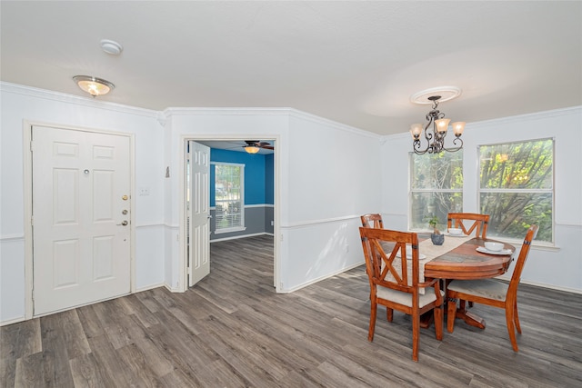 dining space with ceiling fan with notable chandelier, a healthy amount of sunlight, ornamental molding, and dark wood-type flooring