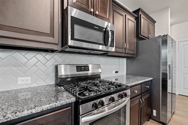 kitchen with tasteful backsplash, dark brown cabinetry, light stone counters, and stainless steel appliances