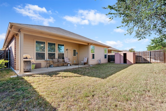 back of property featuring a patio area, a yard, and a storage unit