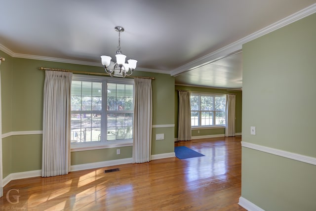 unfurnished dining area featuring light hardwood / wood-style floors, crown molding, a chandelier, and plenty of natural light