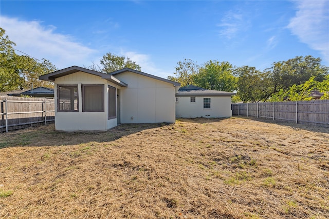 back of property with a yard and a sunroom