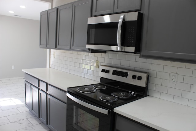 kitchen with appliances with stainless steel finishes, gray cabinetry, and backsplash