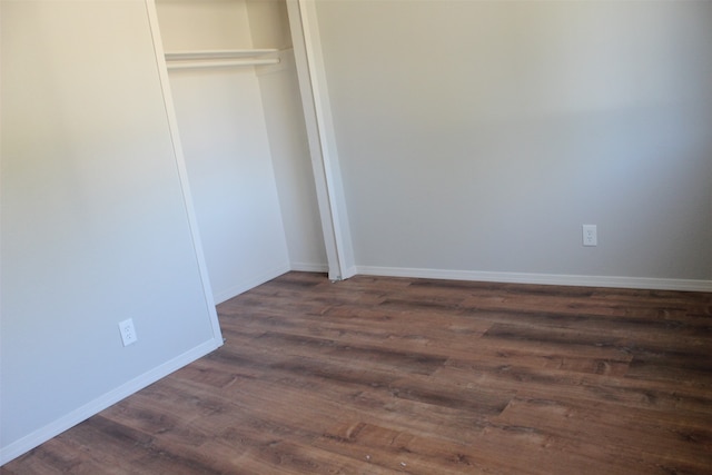 unfurnished bedroom featuring a closet and dark wood-type flooring