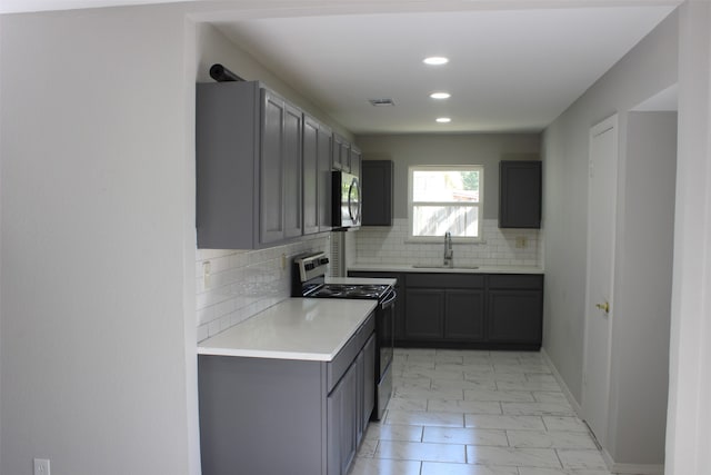 kitchen with gray cabinetry, stainless steel appliances, tasteful backsplash, and sink