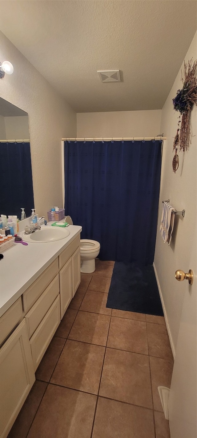 bathroom featuring vanity, a textured ceiling, toilet, and tile patterned flooring