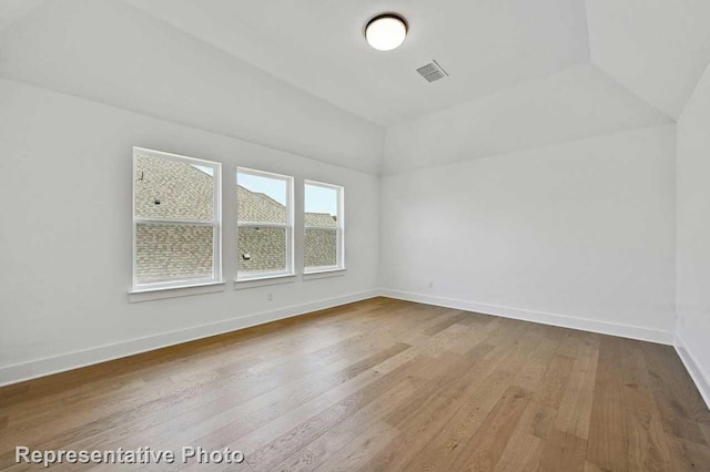 additional living space with lofted ceiling and hardwood / wood-style flooring