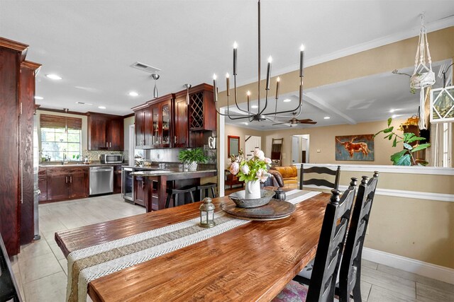 dining space featuring ceiling fan with notable chandelier, crown molding, and sink