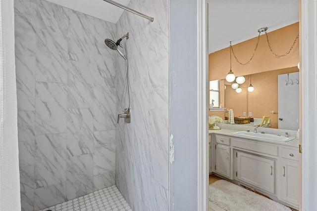 bathroom with a tile shower and vanity