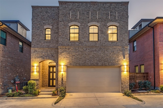 french provincial home with concrete driveway, an attached garage, and brick siding