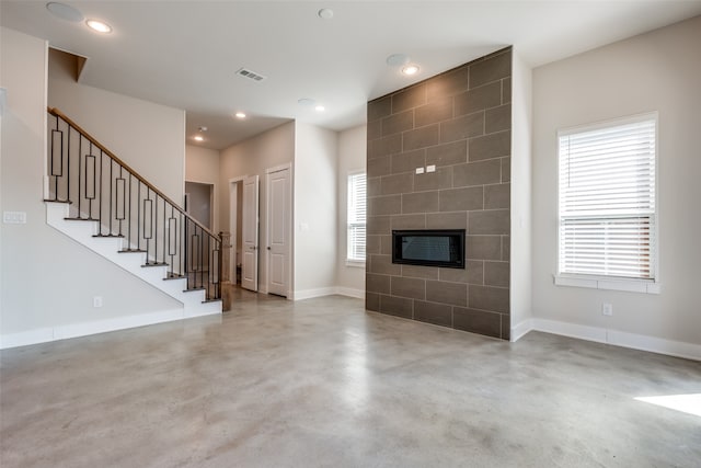 unfurnished living room with a tiled fireplace and concrete flooring