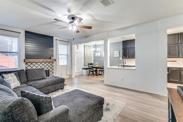 living room featuring light wood-type flooring and ceiling fan with notable chandelier